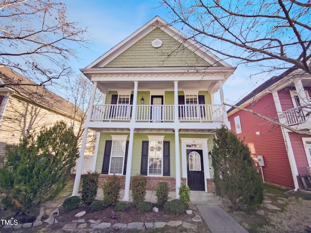 view of front facade featuring covered porch, brick siding, and a balcony