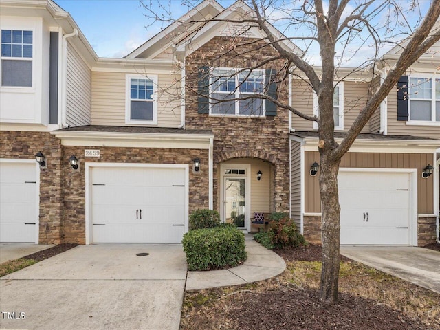 view of property with concrete driveway, an attached garage, and stone siding