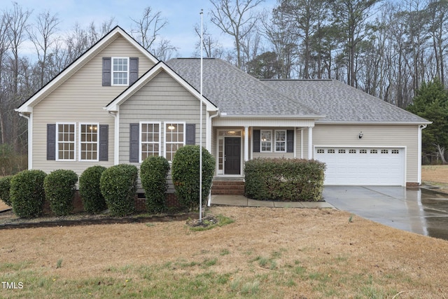 view of front facade with a garage, driveway, a shingled roof, and a front yard