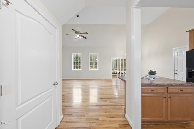 kitchen featuring light wood-style floors, open floor plan, high vaulted ceiling, and a ceiling fan