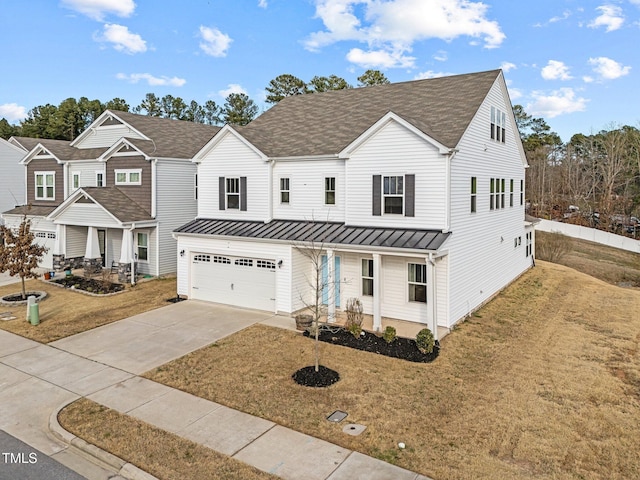 view of front of home featuring driveway, an attached garage, covered porch, a standing seam roof, and a front yard