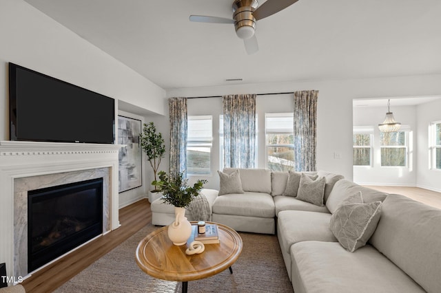 living area featuring ceiling fan, a fireplace, wood finished floors, and visible vents