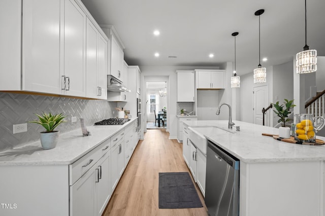 kitchen featuring appliances with stainless steel finishes, light wood-style floors, white cabinets, a sink, and under cabinet range hood