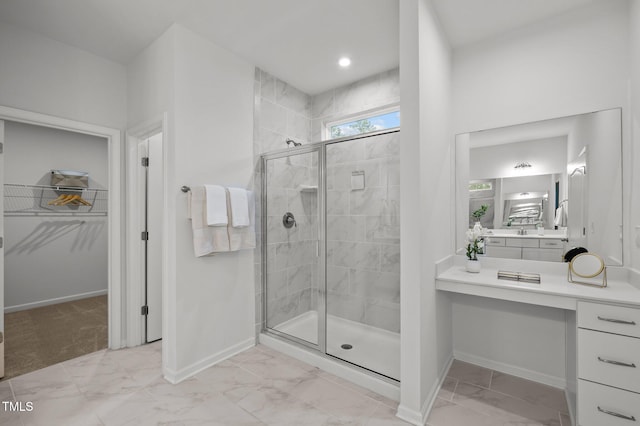 full bath featuring a stall shower, baseboards, marble finish floor, a spacious closet, and vanity