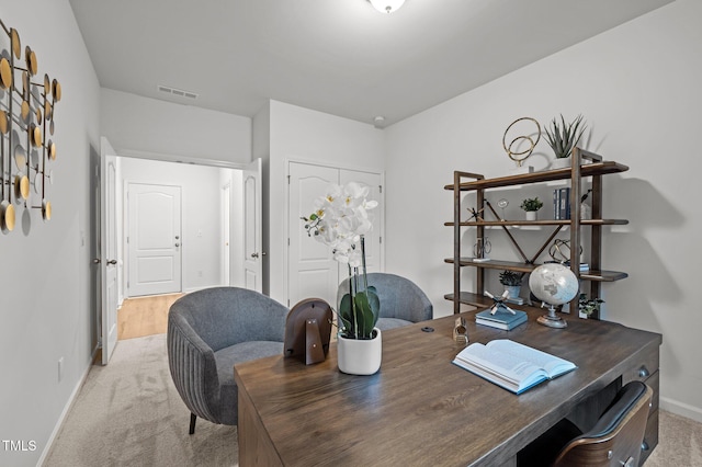 office area featuring baseboards, visible vents, and light colored carpet