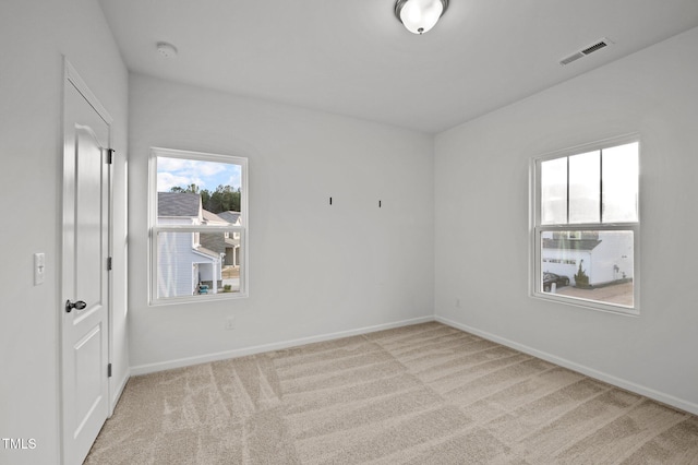 carpeted spare room with visible vents and baseboards