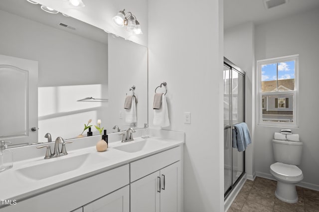 bathroom featuring double vanity, a stall shower, a sink, and toilet