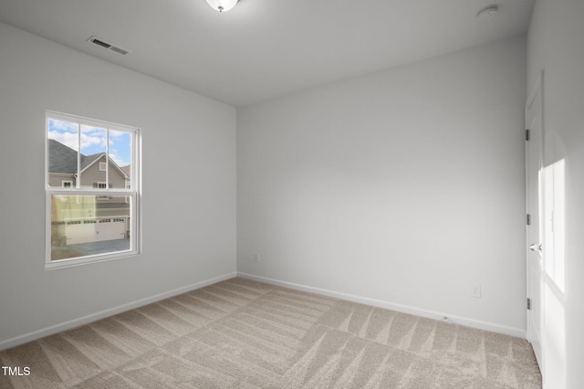 unfurnished room with light colored carpet, visible vents, and baseboards