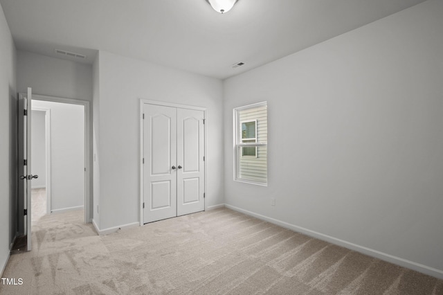 unfurnished bedroom with light carpet, a closet, visible vents, and baseboards