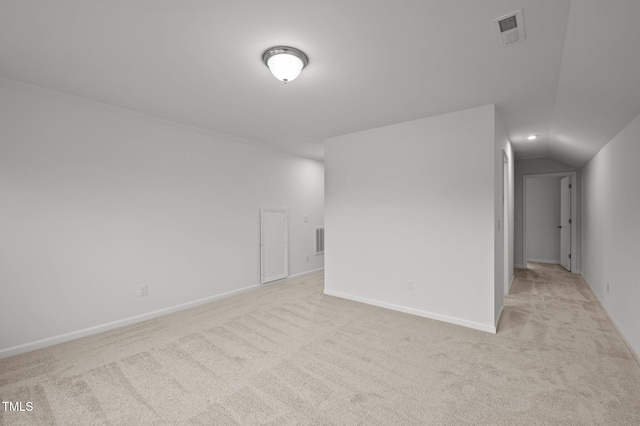 empty room with light carpet, vaulted ceiling, visible vents, and baseboards