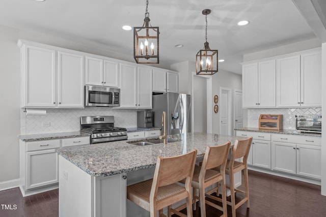 kitchen with a toaster, stainless steel appliances, a sink, white cabinets, and dark wood finished floors