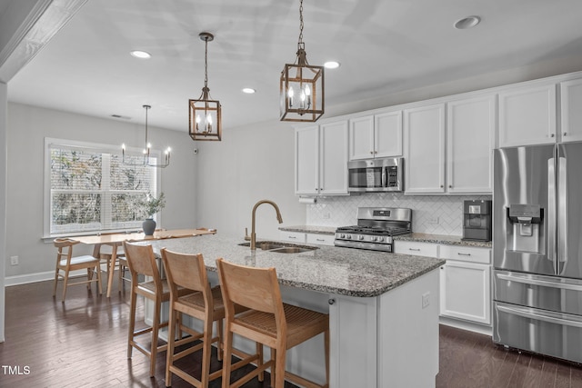 kitchen featuring stainless steel appliances, dark wood-type flooring, a sink, and decorative backsplash