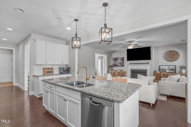 kitchen featuring white cabinets, dishwasher, open floor plan, dark wood-type flooring, and a sink