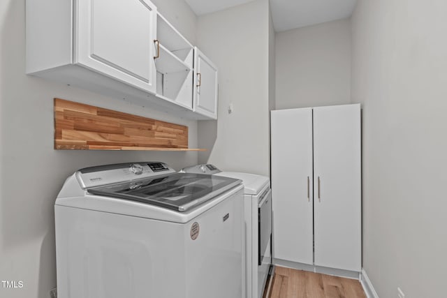 laundry area with cabinet space, light wood-style flooring, and washing machine and clothes dryer