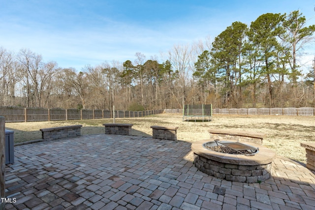 view of patio with a fire pit, a trampoline, and a fenced backyard