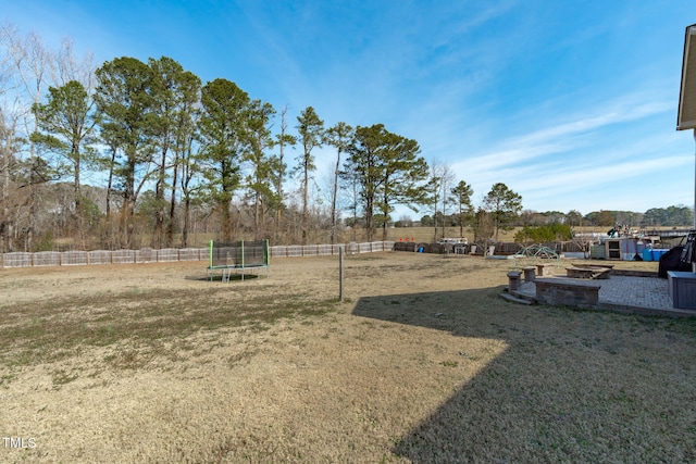 view of yard featuring a trampoline and fence