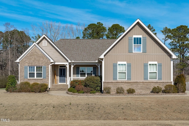 craftsman-style home featuring brick siding, roof with shingles, a porch, and board and batten siding