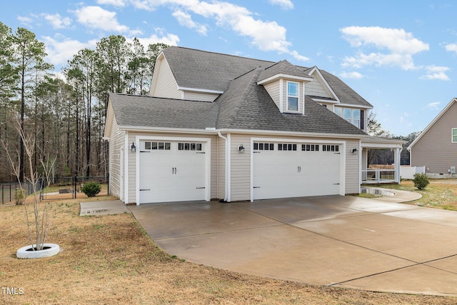 view of front of house with a garage, driveway, fence, and roof with shingles