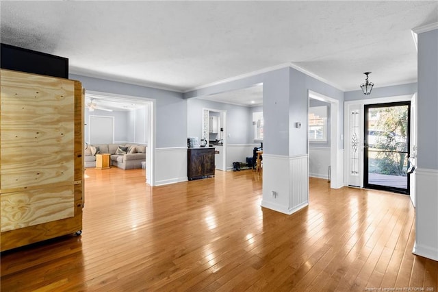 unfurnished living room featuring ornamental molding, a wainscoted wall, and hardwood / wood-style flooring