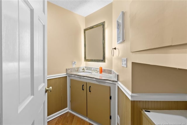 bathroom with a wainscoted wall, vanity, and wood finished floors