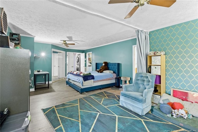 bedroom featuring wallpapered walls, an accent wall, ornamental molding, and wood finished floors