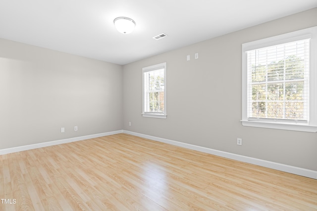 spare room with visible vents, baseboards, and wood finished floors