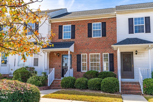 townhome / multi-family property with brick siding and a shingled roof