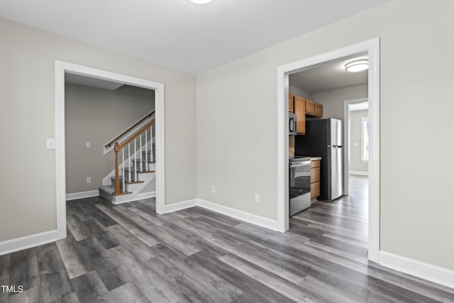 unfurnished room with stairs, baseboards, and dark wood-style flooring