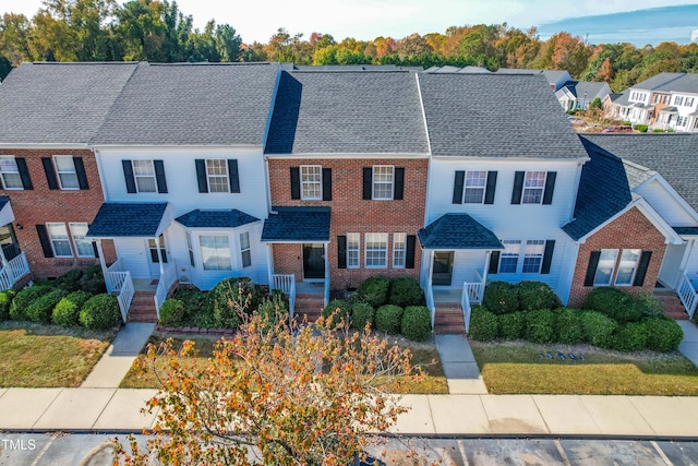 view of property featuring a shingled roof and brick siding