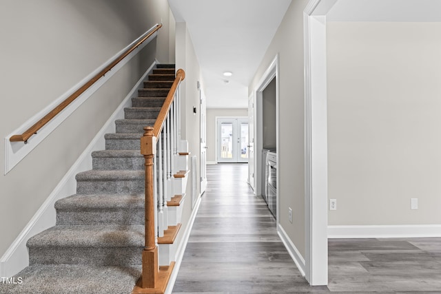 stairs featuring french doors, wood finished floors, and baseboards