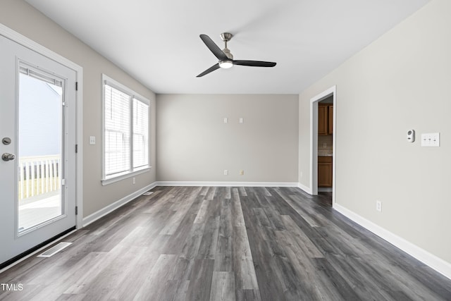 unfurnished room featuring a ceiling fan, dark wood-style flooring, visible vents, and baseboards