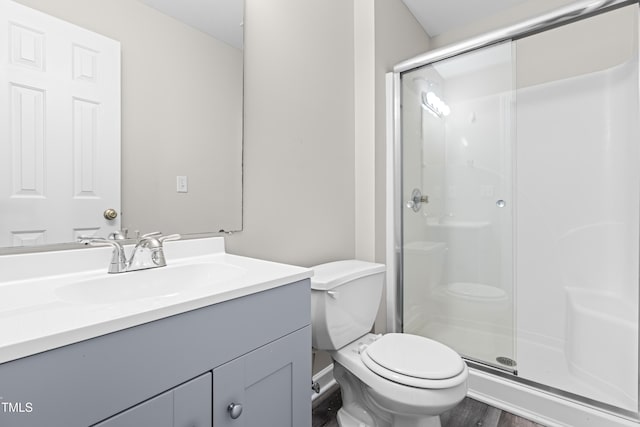 bathroom with vanity, wood finished floors, a shower stall, and toilet