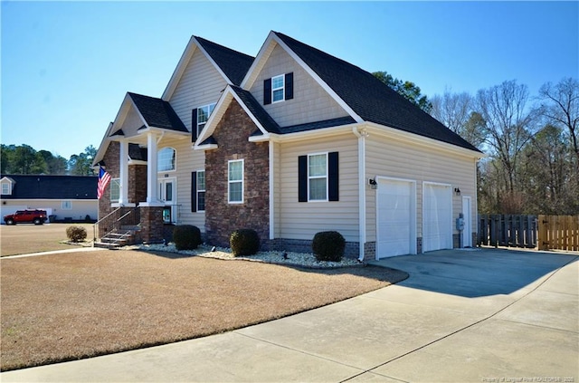 view of front of home featuring stone siding, concrete driveway, fence, and a garage