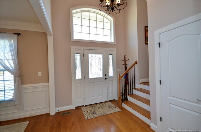 foyer entrance with a chandelier, wood finished floors, visible vents, and a healthy amount of sunlight