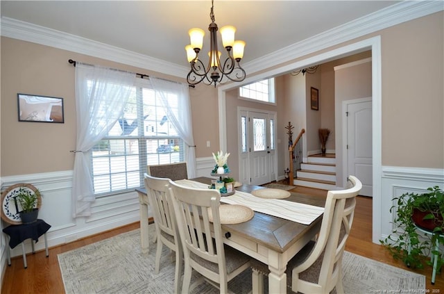 dining area with a healthy amount of sunlight, a wainscoted wall, and a chandelier