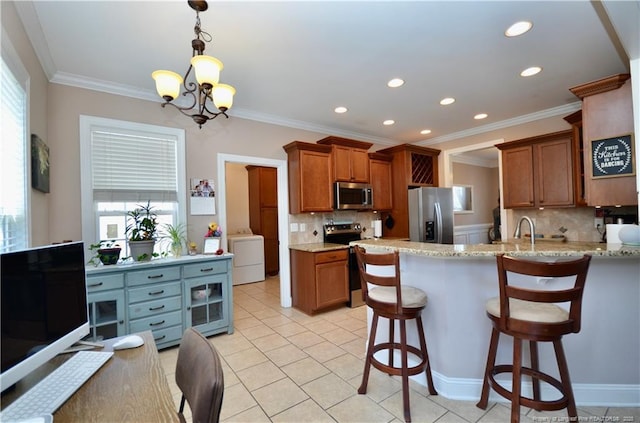 kitchen with stainless steel appliances, washer / clothes dryer, a peninsula, and brown cabinets