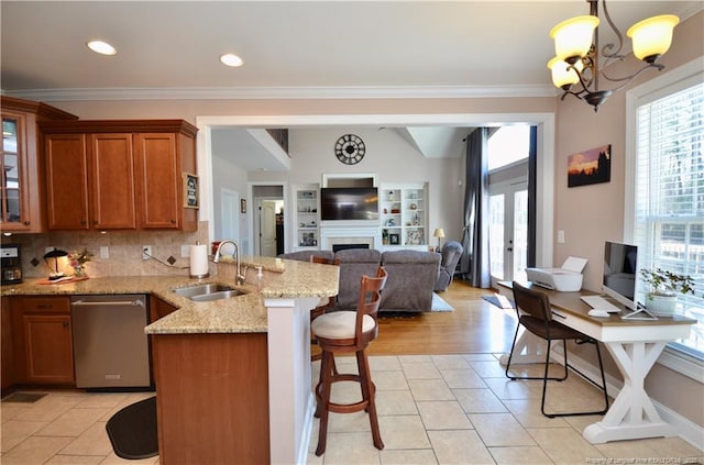 kitchen featuring a healthy amount of sunlight, stainless steel dishwasher, brown cabinetry, and a sink