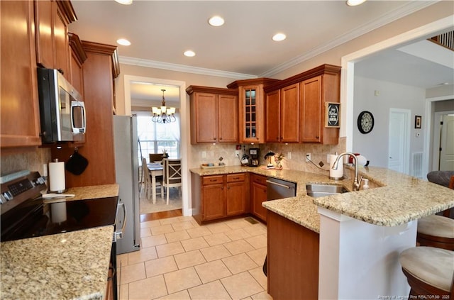 kitchen featuring stainless steel appliances, a peninsula, a sink, and brown cabinets