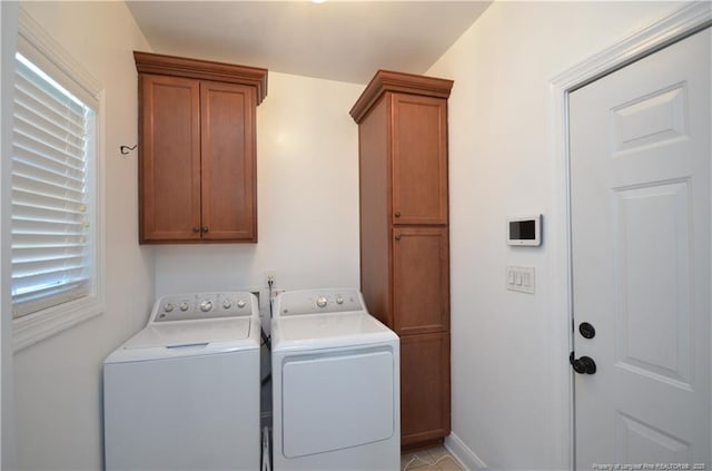 clothes washing area featuring cabinet space and washer and clothes dryer