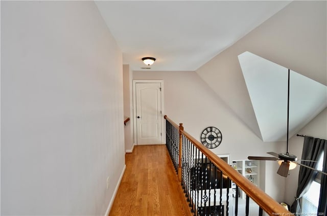 corridor featuring light wood-type flooring, an upstairs landing, and baseboards