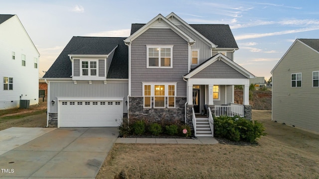 craftsman-style house with a garage, covered porch, stone siding, and cooling unit