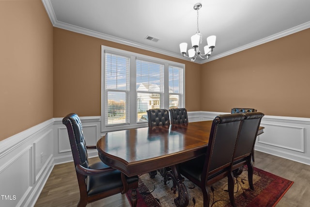 dining area with a wainscoted wall, visible vents, dark wood finished floors, and an inviting chandelier