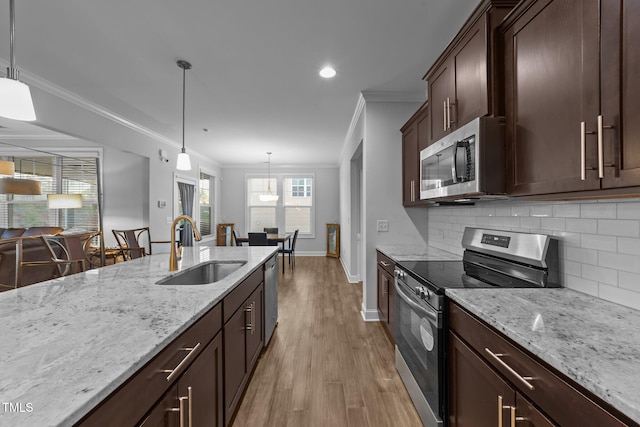 kitchen featuring tasteful backsplash, appliances with stainless steel finishes, a sink, and ornamental molding