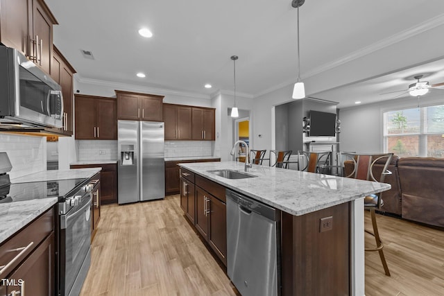 kitchen with light wood-style flooring, a breakfast bar area, open floor plan, stainless steel appliances, and a sink