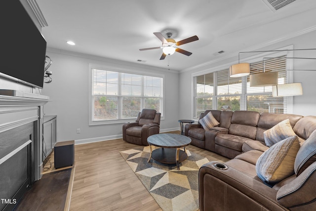 living room with crown molding, a fireplace, visible vents, wood finished floors, and baseboards