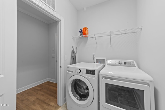 clothes washing area with laundry area, wood finished floors, visible vents, baseboards, and washing machine and clothes dryer