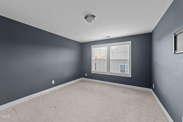 carpeted empty room featuring baseboards and visible vents