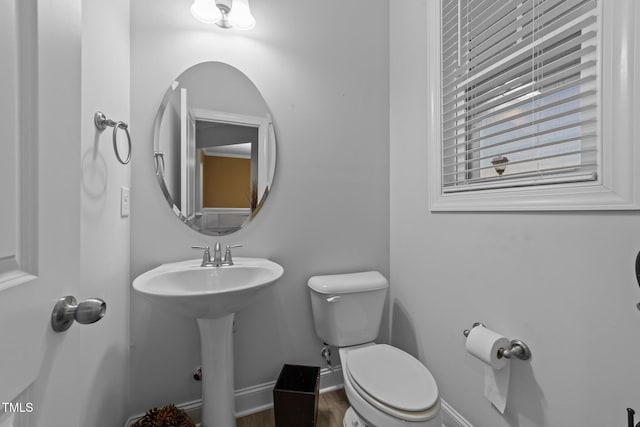 half bath with a sink, toilet, and baseboards