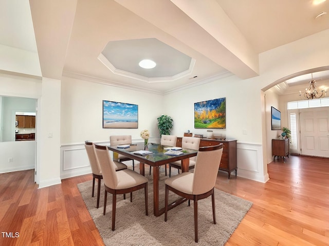 dining space with a chandelier, a decorative wall, wainscoting, and light wood-style floors