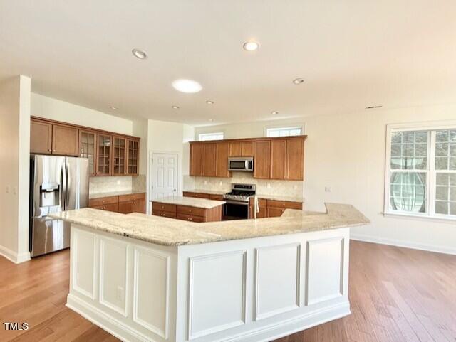 kitchen featuring a large island, brown cabinets, stainless steel appliances, and backsplash